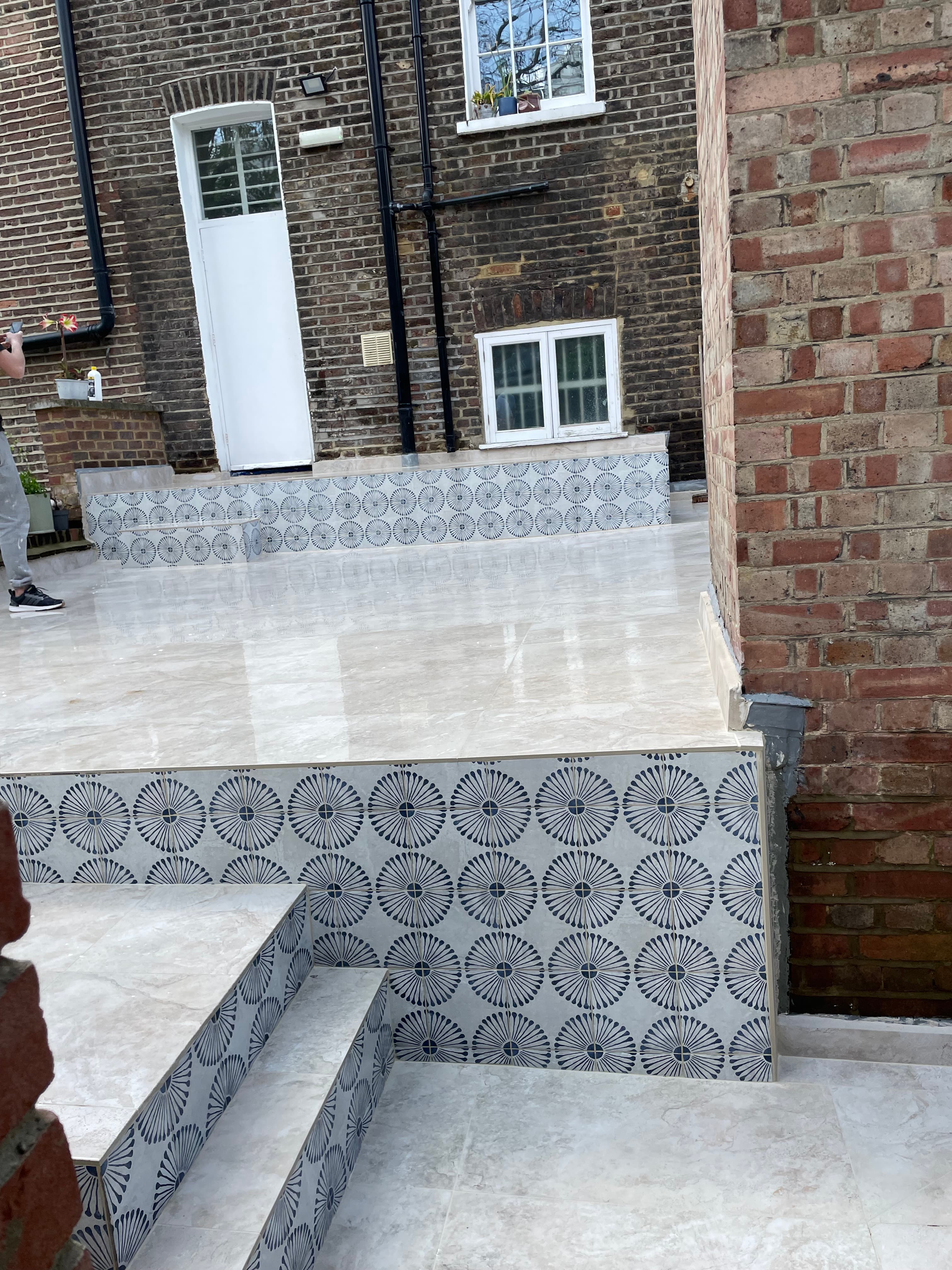 Glossy beige patio tiles and blue patterned decorative tiles on the steps and terrace.